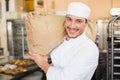 Smiling baker holding bag of flour