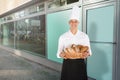 Smiling Baker Holding A Basket Full Of Bread Loaf
