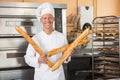 Smiling baker holding three baguettes