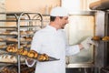 Smiling baker holding trays of croissants