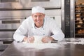 Smiling baker kneading dough on counter