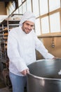 Smiling baker leaning on industrial mixer