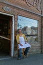 Smiling baker man sitting outside by the door of his bakery waiting his customers