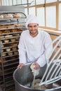 Smiling baker preparing dough in industrial mixer Royalty Free Stock Photo