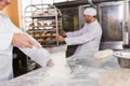 Smiling baker sieving flour on the dough