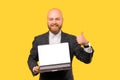 Smiling bald man is showing thumb up while holding laptop with blank screen. Royalty Free Stock Photo