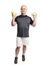 A smiling bald man in a sports uniform with tennis balls in his hands is smiling. Full height. Isolated over white background. Royalty Free Stock Photo