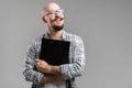 Smiling balded bearded man hold clipboard looking away from camera isolated on a grey background