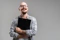 Smiling balded bearded man hold clipboard looking at camera isolated on a grey background