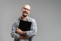 Smiling balded bearded man hold clipboard looking at camera isolated on a grey background