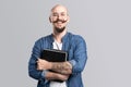 Smiling balded bearded man hold clipboard looking at camera isolated on a grey background