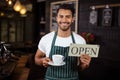 Smiling barista holding coffee and open sign Royalty Free Stock Photo