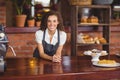 Smiling barista leaning on counter