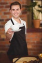 Smiling barista offering cup of coffee to camera Royalty Free Stock Photo