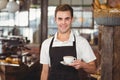 Smiling barista offering cup of coffee to camera Royalty Free Stock Photo