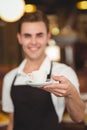 Smiling barista offering cup of coffee to camera Royalty Free Stock Photo