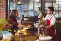 A smiling barista serving a client