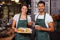 Smiling baristas holding sandwiches and hot milk Royalty Free Stock Photo