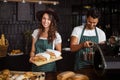 Smiling baristas holding sandwiches and making coffee Royalty Free Stock Photo