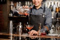 Smiling barman adding red alcoholic drink into the cocktail glass Royalty Free Stock Photo