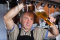 Smiling barman is pouring unbottled beer for next client