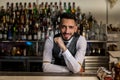 Smiling barman standing at bar counter