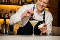 Smiling barman in white shirt and apron decorating a cocktail with a birch leaf Royalty Free Stock Photo