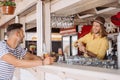 smiling bartender and client with beer bottle looking at each other