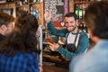 Smiling bartender pouring beer in glass for customers