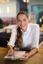 Smiling bartender writing on clipboard at bar counter