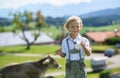 Smiling Bavarian boy drink milk on the meadow with cow .Alps in background. Germany. Royalty Free Stock Photo