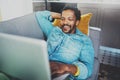 Smiling bearded African man spending free time in sofa and using digital tablet at modern home.Concept of young people Royalty Free Stock Photo