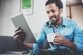 Smiling bearded African man using tablet for reading morning news and drinking black coffee at home.Concept people Royalty Free Stock Photo
