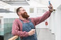 Smiling bearded barber worker drinking coffee from a paper cup, talking on a video call.Time to take break