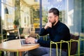 Smiling bearded businessman on the phone working on laptop outside the cafe Royalty Free Stock Photo