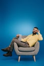 Smiling bearded businessman sitting in armchair with laptop Royalty Free Stock Photo