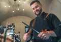 Smiling bearded chef cook dressed black uniform with apron sharpening knife with Honing Steel tool. Professional occupation, hard