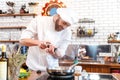 Smiling bearded chef cook standing and cooking in frying pan