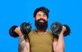 Smiling bearded man with dumbbells up in hands. Strong sportsman doing workout in fitness gym. Athletic muscular man Royalty Free Stock Photo