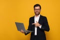 Smiling bearded man pointing at laptop on orange background Royalty Free Stock Photo