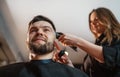 Smiling bearded Man portrait while undercut hairstyle hairdressing in Hair Salon by young hairdresser female. Modern barber shop Royalty Free Stock Photo