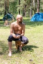 Smiling bearded man of 40 years in campground. tourist, traveler or explorer. with a torso sits on stump in forest