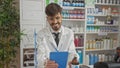 Smiling bearded pharmacist using tablet in a modern drugstore filled with diverse products Royalty Free Stock Photo