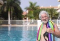 Smiling bearded senior man with white hair standing in the swimming pool with a colorful towel on shoulders - active elderly Royalty Free Stock Photo