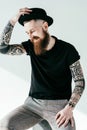 smiling bearded tattooed man touching hat