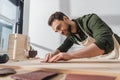 Smiling bearded workman sanding wooden board