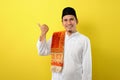Smiling bearded Young Asian muslim man pointing the copy space to presenting something Royalty Free Stock Photo
