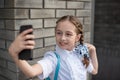 Smiling beatiful preteen girl taking a selfie outdoors. Child taking a self portrait with mobile phone. technology Royalty Free Stock Photo