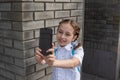 Smiling beatiful preteen girl taking a selfie outdoors. Child taking a self portrait with mobile phone. technology Royalty Free Stock Photo