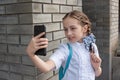 Smiling beatiful preteen girl taking a selfie outdoors. Child taking a self portrait with mobile phone. technology Royalty Free Stock Photo